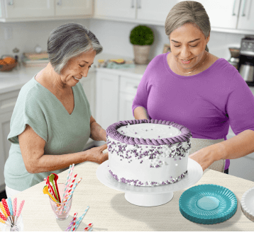 Two women decorating a cake.